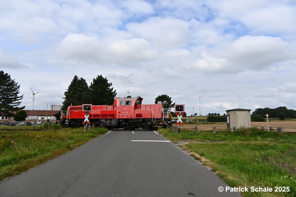 Diesellokomotive 261 029-3 in verkehrsrot der DB Cargo AG passiert nach der Bedienung des Gleisanschlusses der Firma ExxonMobil in Barenburg einen mit Blicklichtern gesicherten Bahnübergang