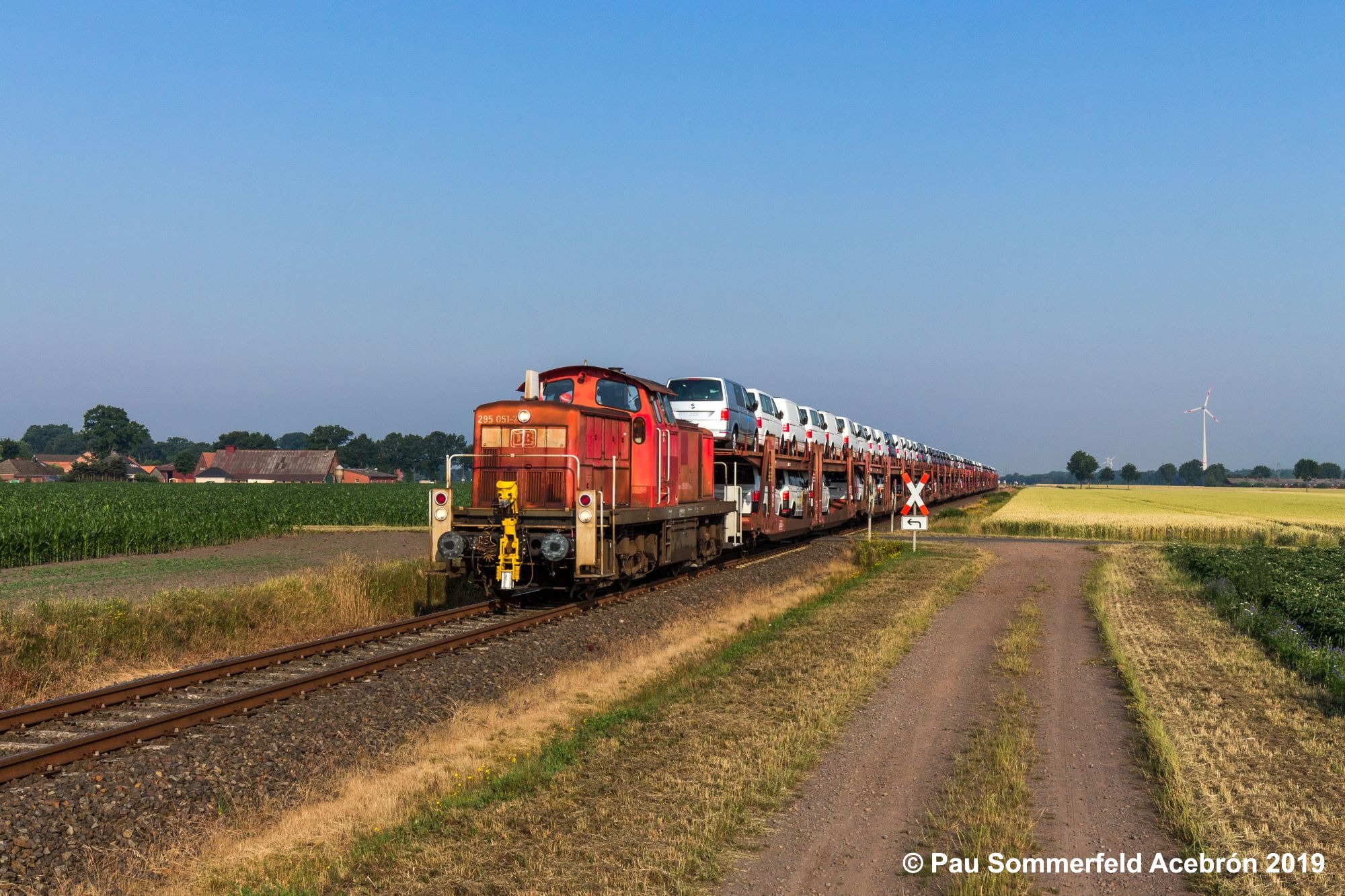 Diesellok 295 051 in verkehrsrot der DB Cargo AG erreicht mit einem Autotransportzug Rehden-Wetschen und passiert gerade einen nicht-technisch gesicherten Bahnübergang