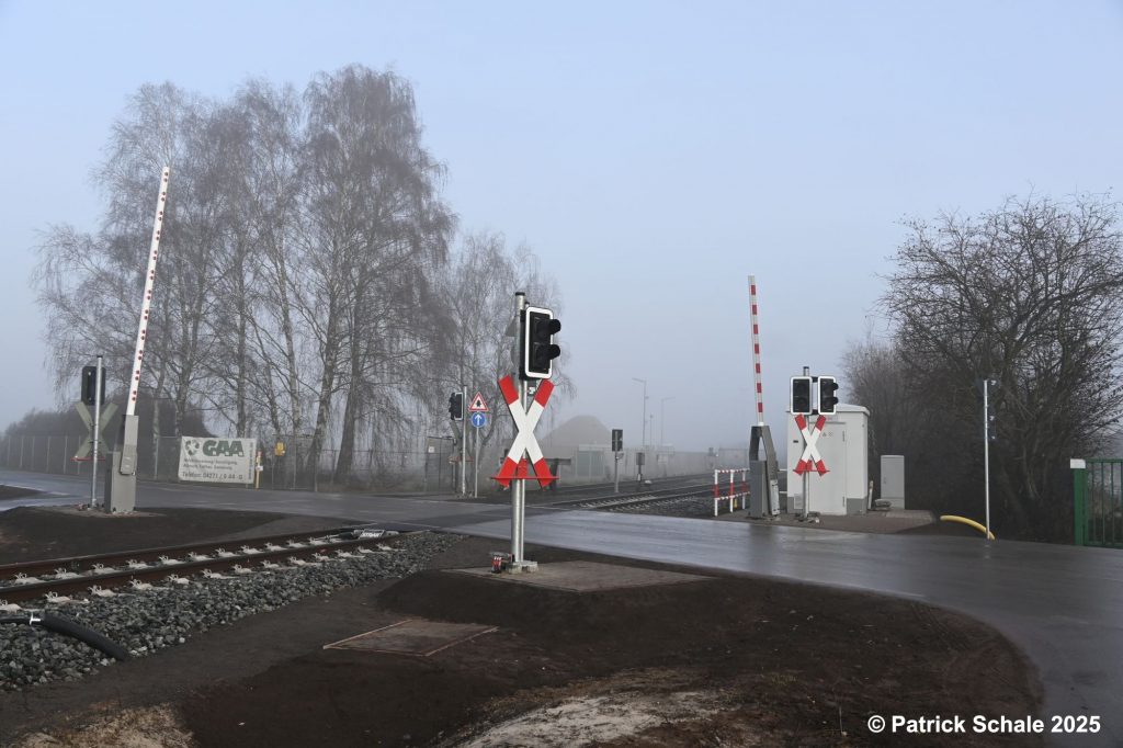 Erneuerter Bahnübergang mit neuen Lichtzeichenanlagen, Halbschranken und neuem Schalthäuschen am Birkenkampsweg an einem nebeligen Dezembertag