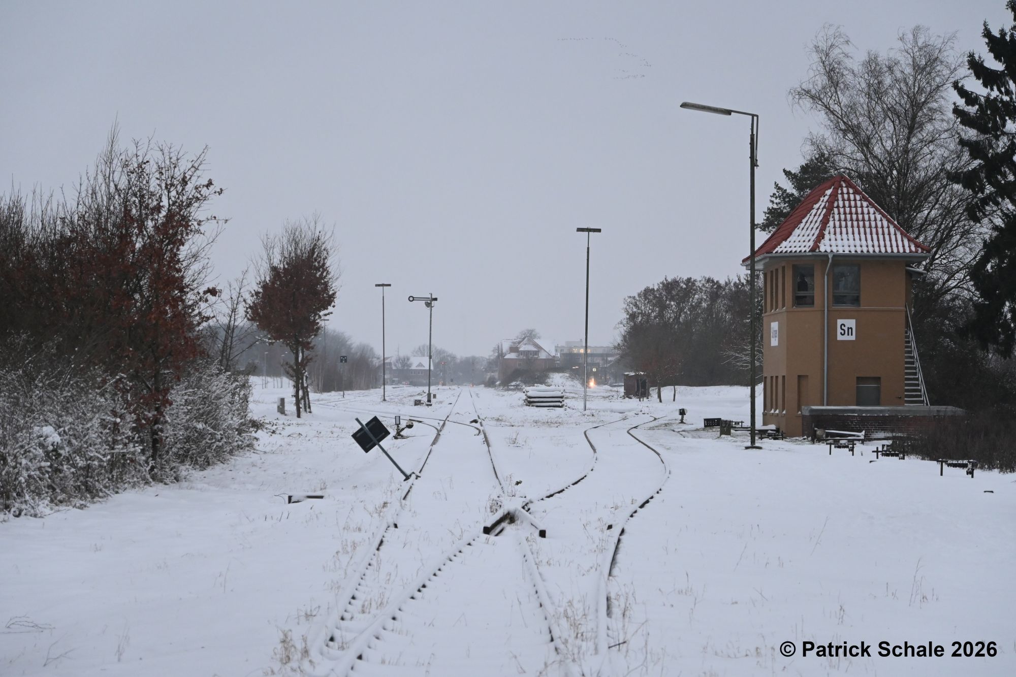 Blick vom Bahnübergang Hasseler Feldweg in Richtung Süden auf den eingeschneiten Bahnhof Sulingen, rechts Stellwerk Sn