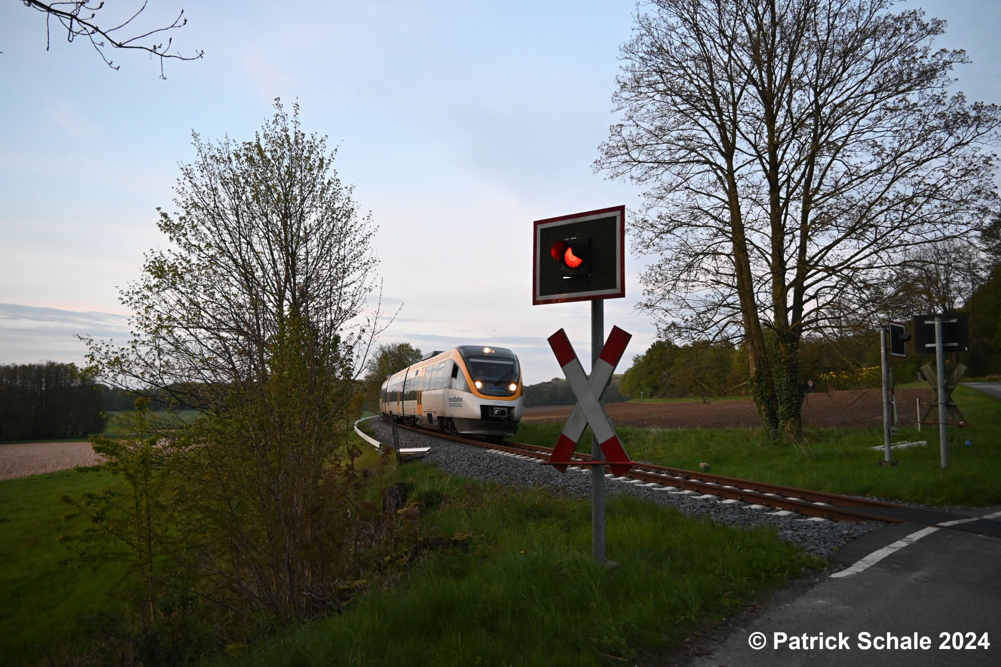 Dieseltriebwagen der Eurobahn auf dem Weg nach Bielefeld Hbf passiert im letzten Licht des Tages den Bahnübergang Zur Schirmke kurz vor dem Bedarfshaltepunkt Mesch Neue Mühle
