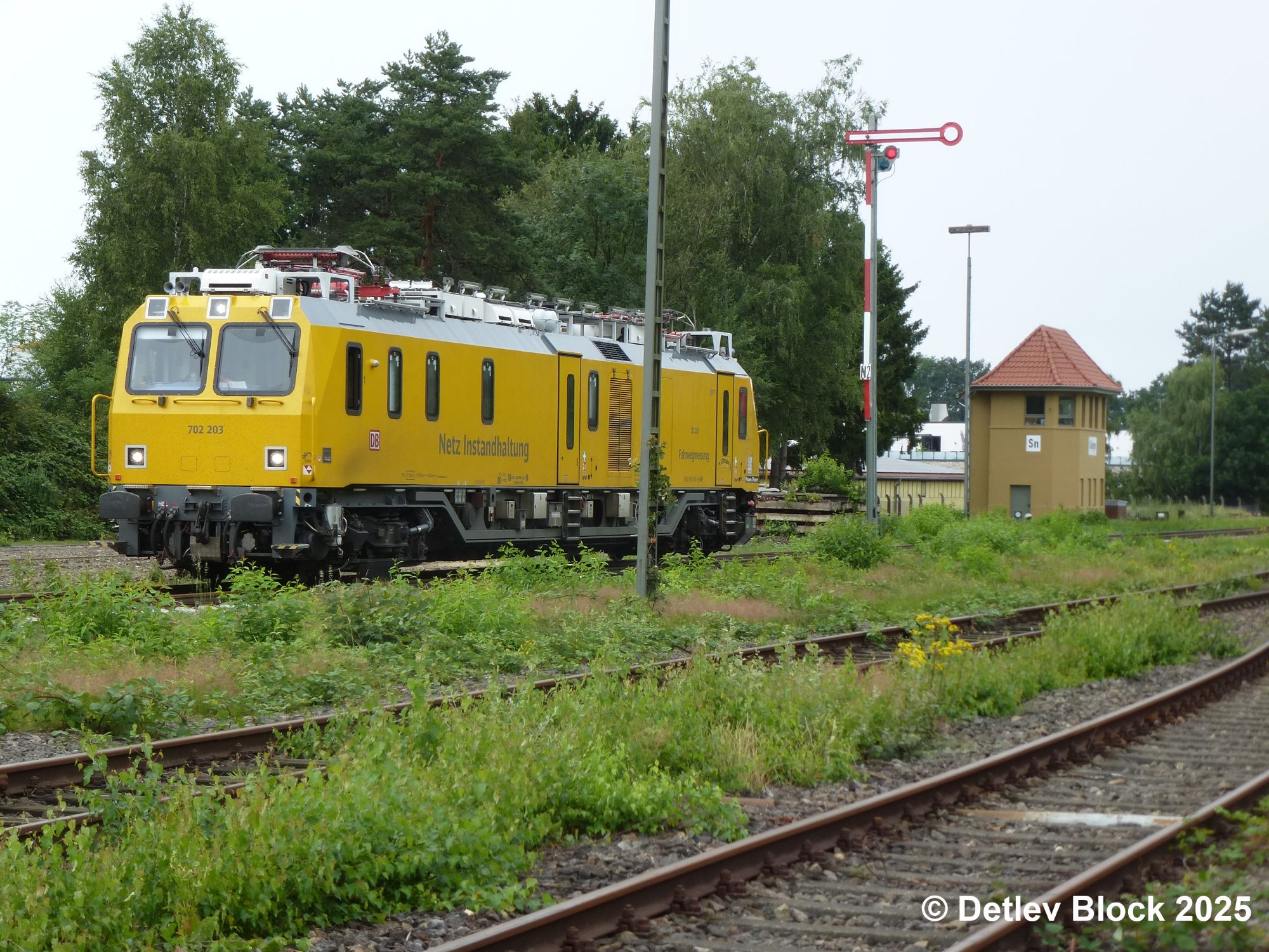 Gelber Gleismesszug der DB InfraGO AG steht auf Gleis 2 im Sulinger Bahnhof. Im Hintergrund ist das frisch sanierte Stellwerk Sn zu sehen.