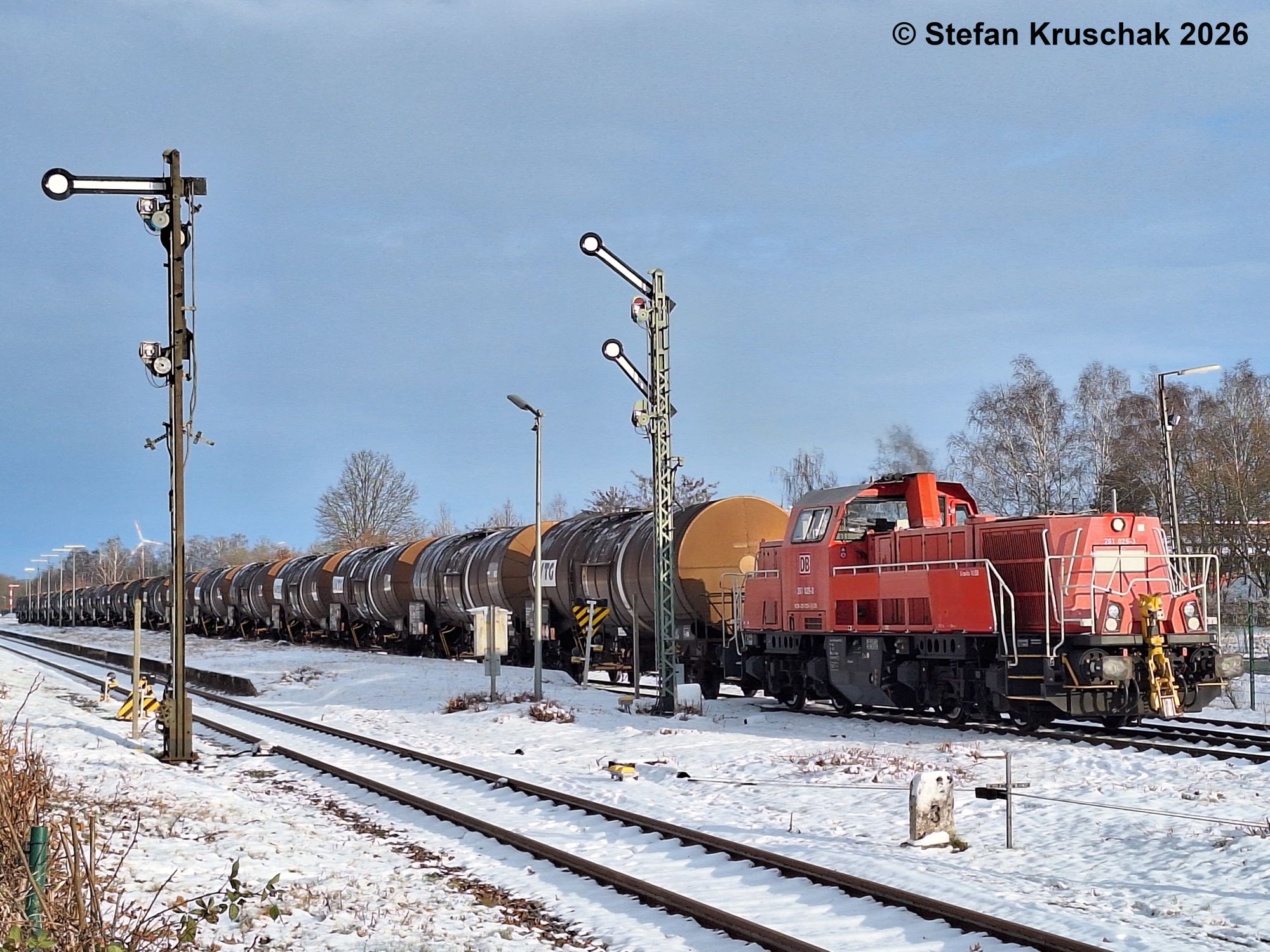 Diesellokomotive 261 029-3 der DB Cargo AG in verkehrsrot fährt mit einem Kesselwagenzug auf HP 2 (Langsamfahrt) aus dem verschneiten Bahnhof Sulingen aus