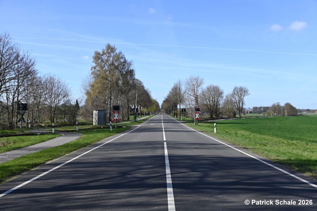 Bahnübergang B 214 Dahlskamp mit Blinklichtern und Halbschranken, links Fuß- und Fahrradweg, Blinkrichtung Diepholz