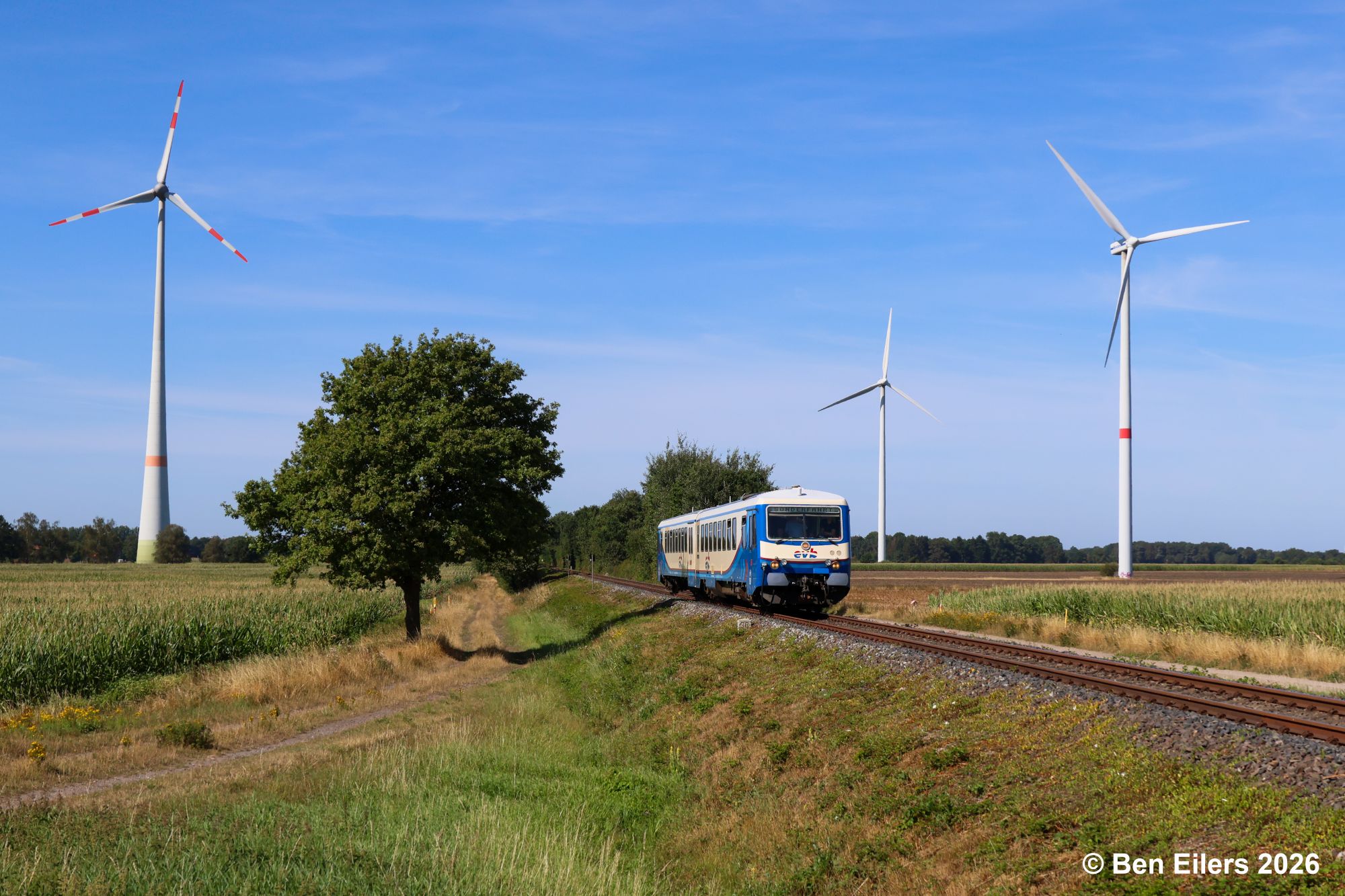 Sonderzugverkehr zum Reload Festival mit dem Triebwagen der Baureihe 628 der evb zwischen landwirtschaftlichen Flächen und Windkraftanlagen in Groß Lessen