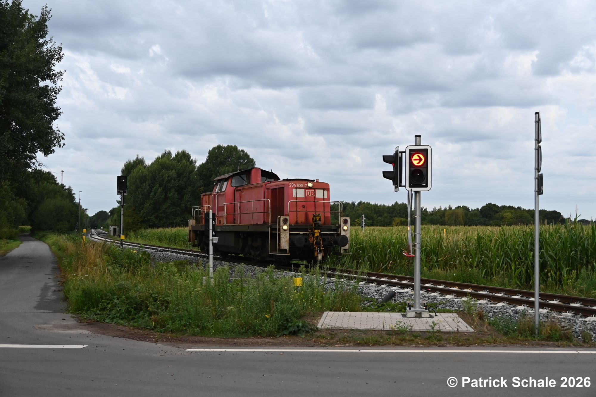 Diesellokomotive der Baureihe 294 in verkehrsrot passiert im Bahnhof Barenburg die noch ziemlich neuen Lichtzeichen des Bahnübergangs Birkenkamps Weg.