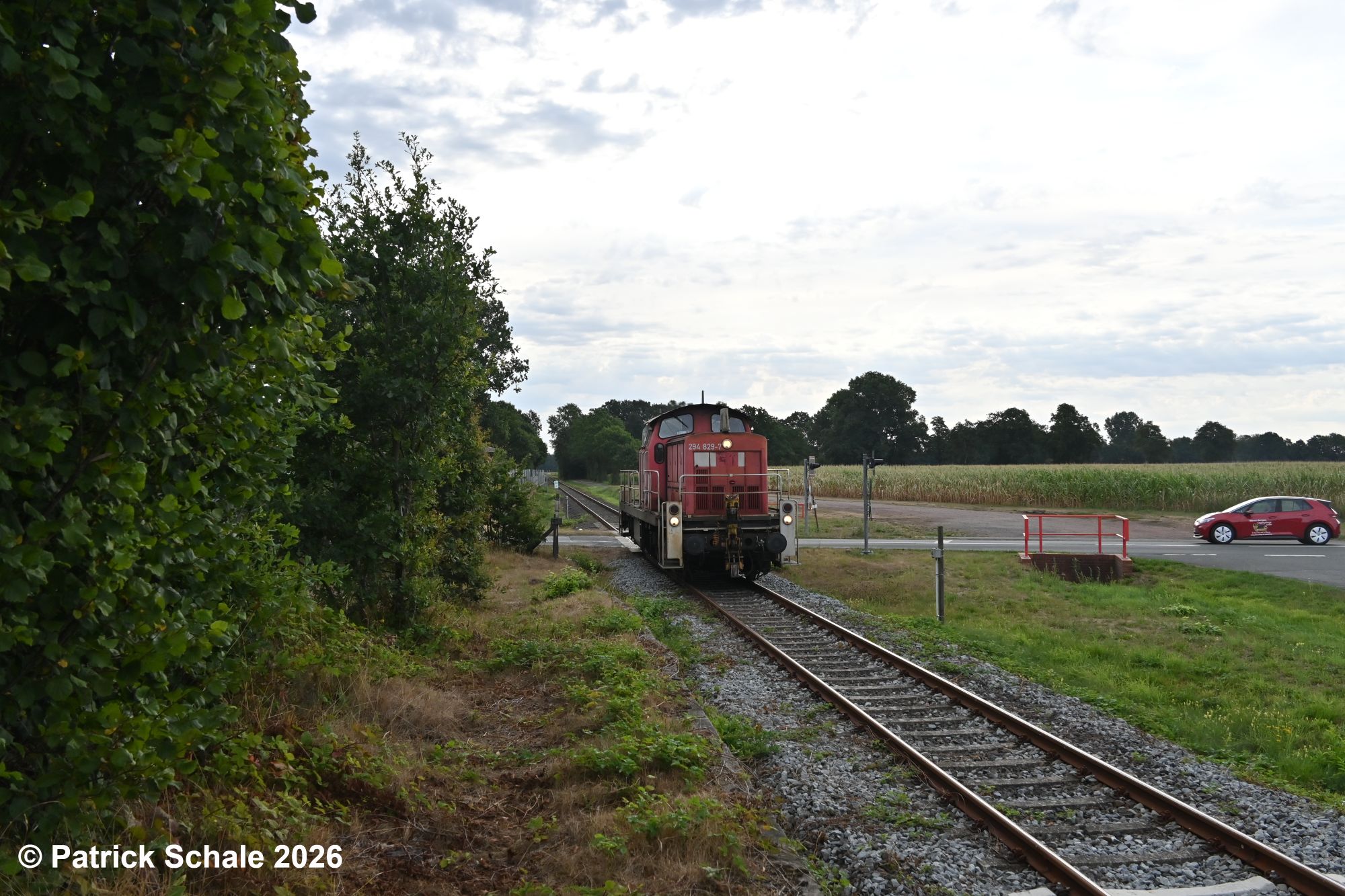 Diesellokomotive der Baureihe 294 in verkehrsrot hat gerade den Bahnübergang Barnstorfer Straße im Bereich des ehemaligen Bahnhofs Barver passiert und fährt weiter Richtung Diepholz.