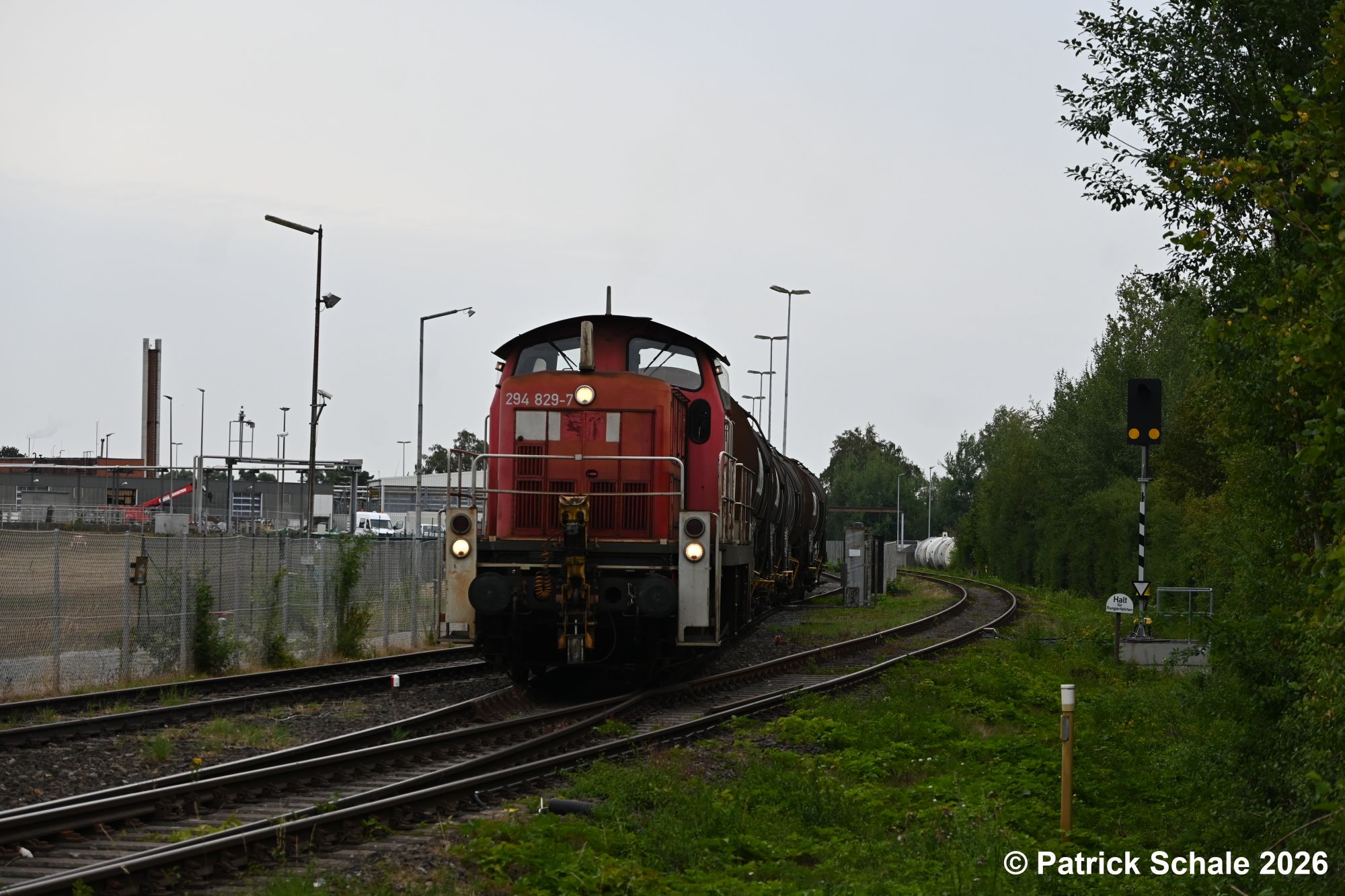 Eine Diesellokomotive der Baureihe 294 zieht mit rohölbeladene Kesselwagen aus dem Barenburger Werk von ExxonMobil. Rechts ist das Streckengleis nach Sulingen mit einem Bahnübergangüberwachungssignal zu sehen.