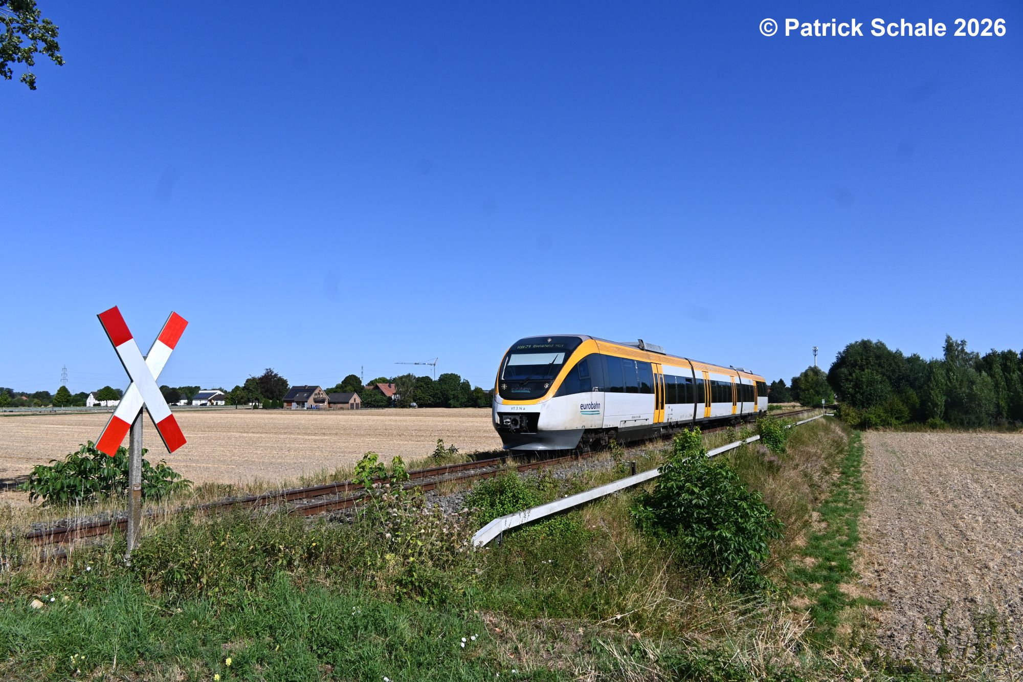 Die RB 71 mit Zielbahnhof Bielefeld Hbf rollt dem nächsten Halt Lübbecke (Westf) entgegen und passiert nun den Bahnhübergang Rampenweg.